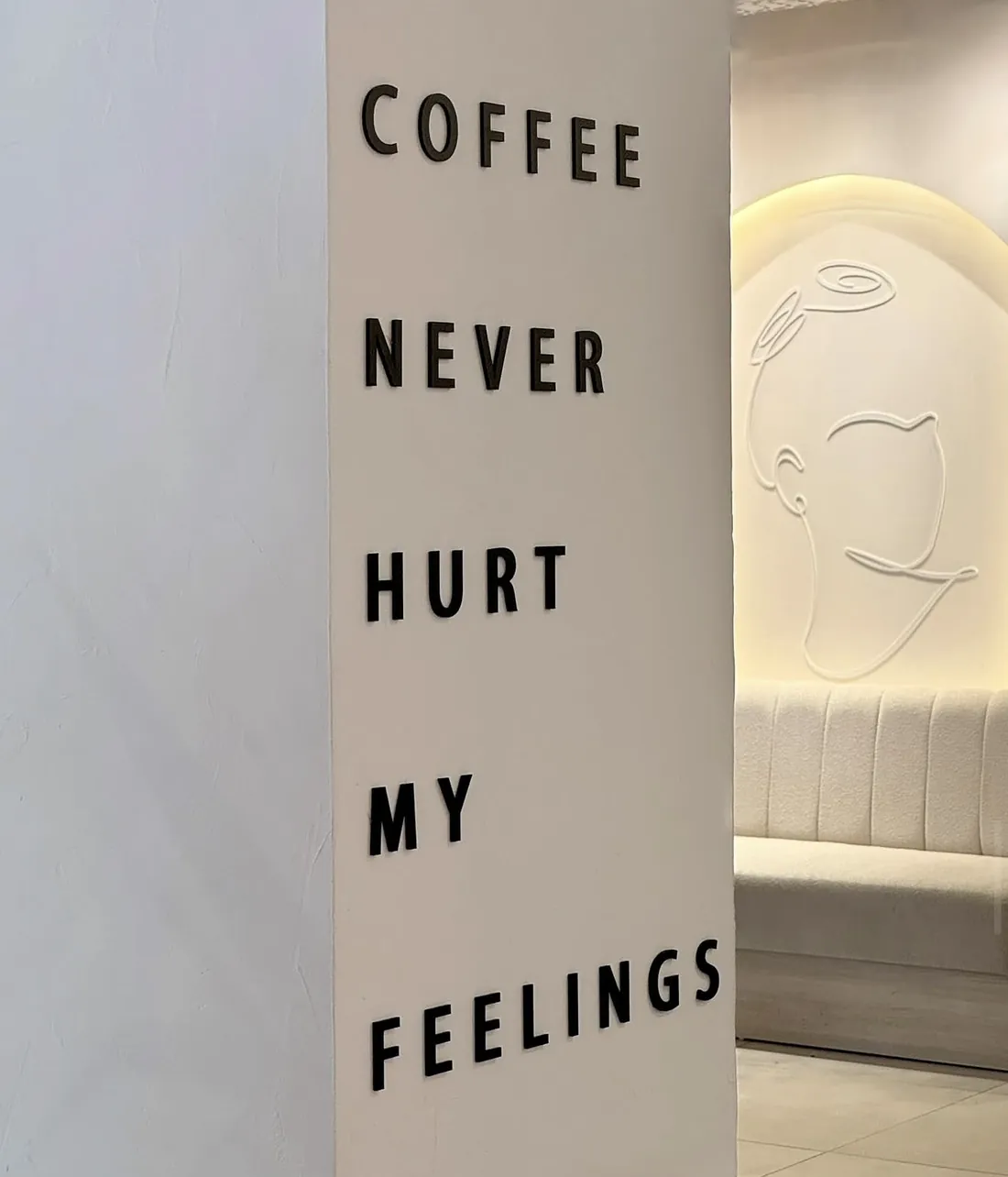 Schriftzug „Coffee never hurt my feelings“ an der Wand, dahinter eine Sitzbank