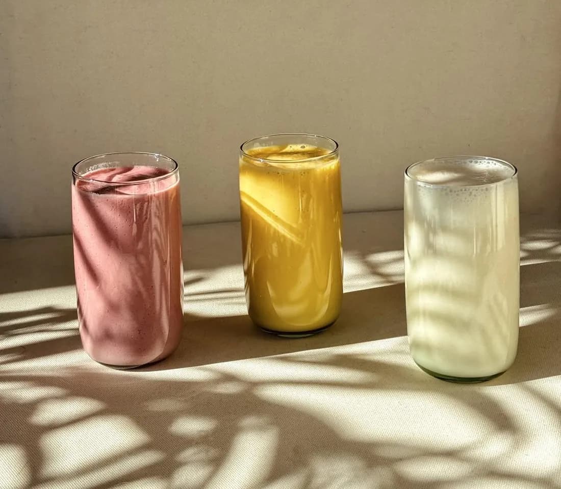 Drei Milkshakes in Himbeere, Mango und Vanille im Sonnenlicht